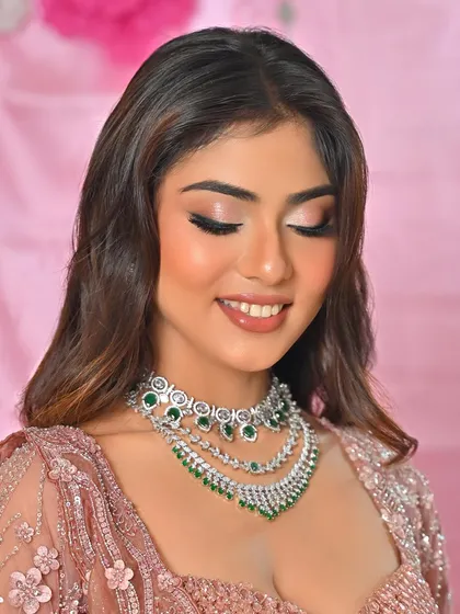 A happy, smiling shot of the model in her pink lehenga. The makeup is fresh and youthful.