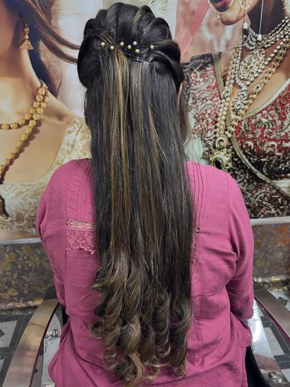 A simple and elegant half-up hairstyle. The top section is styled with a slight puff and decorated with pearls, while the rest of the hair is left straight with curled ends.