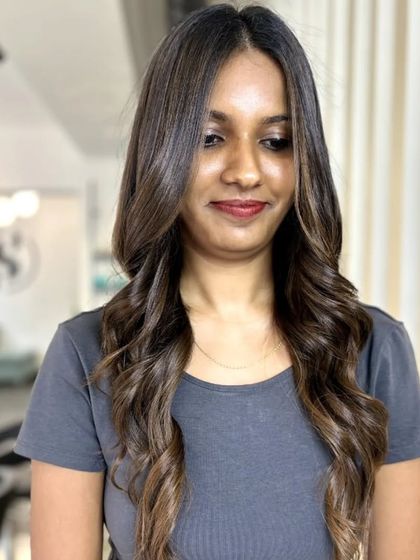 A happy client showing off her new highlights and soft waves.