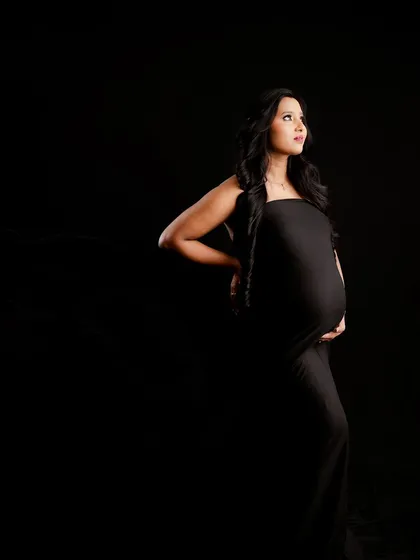 A powerful and dramatic solo portrait that celebrates the strength of motherhood. Using moody, low-key lighting, I focus on the beautiful silhouette of the baby bump against a classic black background.