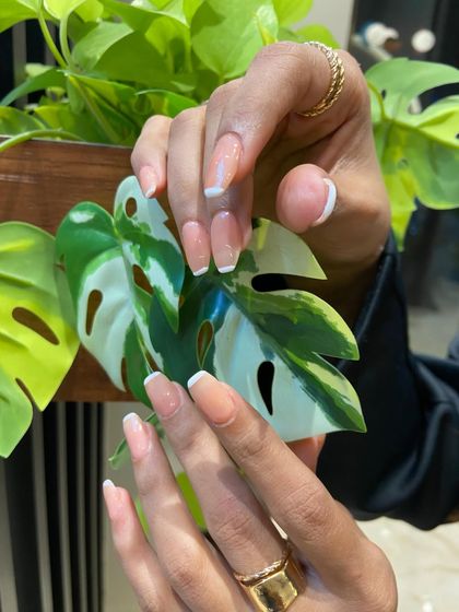 Posed against a vibrant green leaf, the clean white tips and neutral base of this French manicure really pop. It’s a fresh and modern take on a classic.