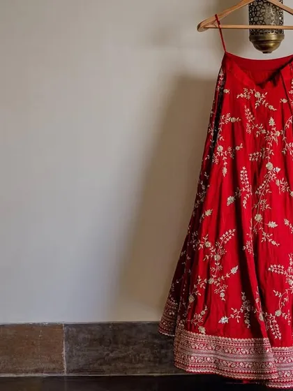 A close-up of the bride's stunning red wedding lehenga, hanging in her room at Alila Fort. The intricate embroidery hints at the grandeur of the day to come.