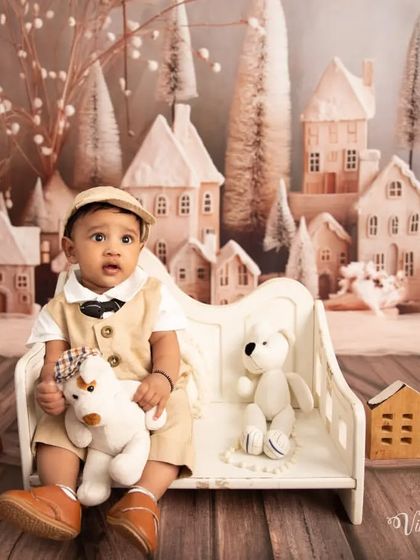 Cuddling with his teddy bear in a winter village. This charming photo captures a sweet moment as the baby holds his stuffed animal during the themed session.