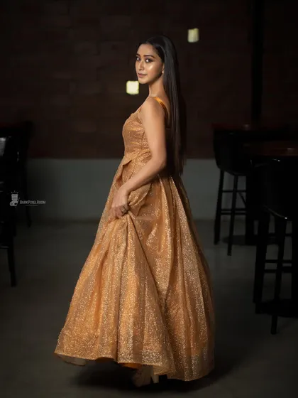 Elegance meets mood. This shot uses low-key lighting in an indoor setting to create a cinematic feel, highlighting the texture of the gown and the subject's quiet grace. It's a perfect example of a fashion-forward portrait.
