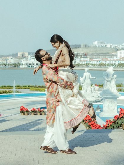 The groom lifts the bride in a playful and romantic pose during their Mehendi function in Vietnam.