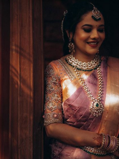 A warm, softly lit portrait of the bride in her gorgeous silk saree. The lighting enhances the rich colors and the intricate details of her jewelry.