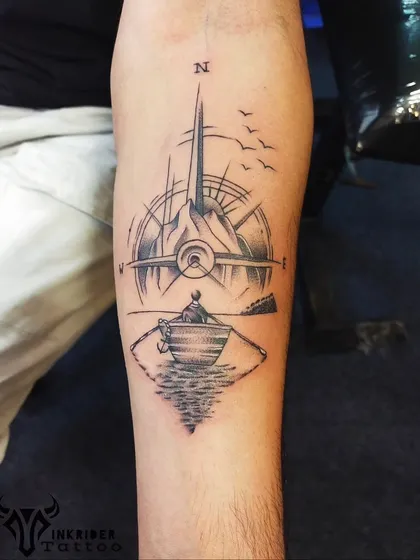 Another custom travel tattoo, this one featuring a person rowing towards a mountain range that merges with a compass and an airplane. It's a story of adventure and finding your own direction.