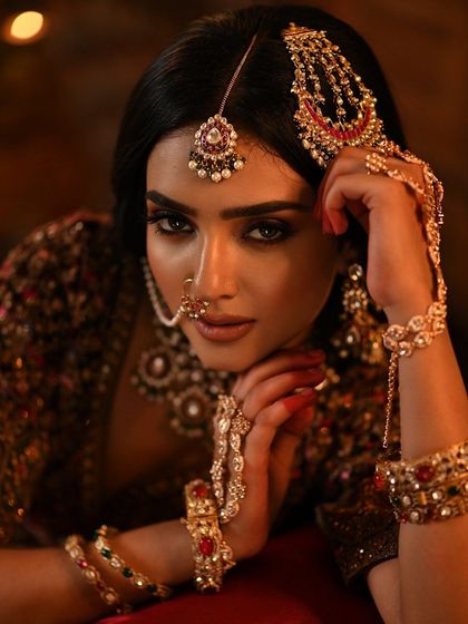 A close-up on the face, highlighting the dramatic eye makeup, the traditional nath, and the intricate jewelry.