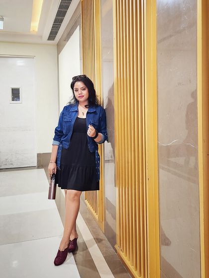 A full-length shot of the casual denim and dress look, showing the stylish burgundy shoes.