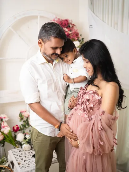 A heartwarming family maternity photo. The older son snuggles up to his father while the mother cradles her bump, creating a portrait full of love and connection.