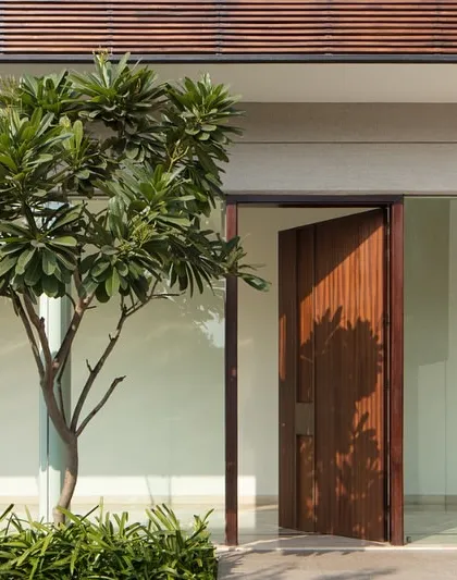 The entrance to a home sets the tone. This large pivoting wooden door creates a grand yet welcoming threshold, blurring the line between the exterior landscape and the interior space.