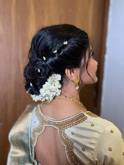 A detailed shot of the elegant hair bun, decorated with fresh white flowers and delicate hairpins. This hairstyle is a timeless choice for an engagement ceremony.