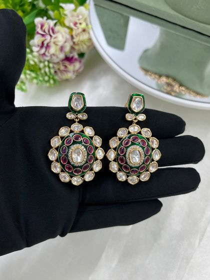 A pair of statement kundan earrings with green and red meenakari, perfect for adding a pop of color.