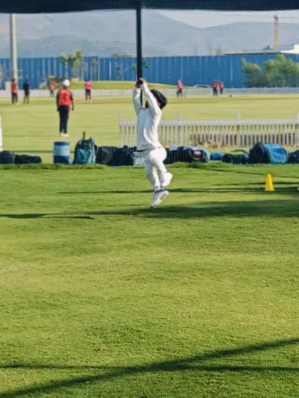 A young cricketer leaps to catch the ball during a practice session, showing great athleticism and commitment.