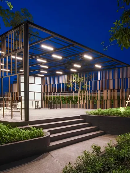 An outdoor pavilion at night, illuminated by integrated lighting within the raftered ceiling. This image shows how thoughtful lighting design can turn a pergola into a functional and atmospheric space after dark.