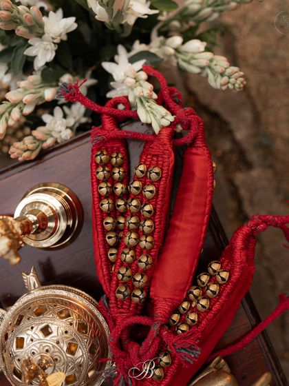 A close-up of bright red ghungroo anklets, placed alongside other decor elements. These traditional items add an authentic and vibrant touch, celebrating the cultural richness of Indian weddings.