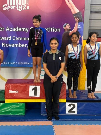 Our coach stands proudly with her students on the podium. This moment represents the culmination of teamwork, training, and a shared passion for gymnastics.