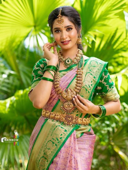A model adorned in a beautiful green and pink Kanchipuram silk saree, complete with traditional temple jewelry, showcasing a complete bridal look.