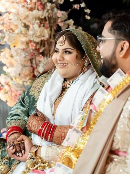 A happy moment between the bride and groom. The bride's hands, decorated with a deep henna stain, are a beautiful part of the picture.