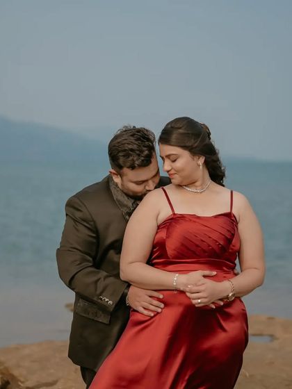 A tender moment from a pre-wedding shoot by the lake, with the groom-to-be kissing his partner's shoulder.