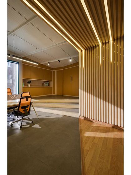 A detail of the custom lighting integrated into the wood-slatted ceiling and walls at the Kadence Office. This feature not only illuminates the workspace but also accentuates the rhythmic, linear pattern that defines the entire design concept.