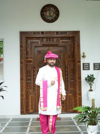A full view of the groom's rental attire against a grand backdrop. The combination of white and pink is both traditional and eye-catching.