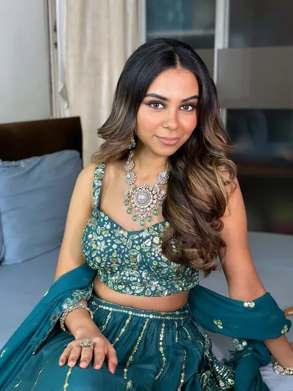 The complete look, showing how the teal green lehenga is beautifully complemented by the warm, earthy tones of the makeup.