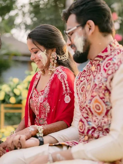 The bride smiles, her face smeared with haldi, capturing the true spirit of the ceremony.
