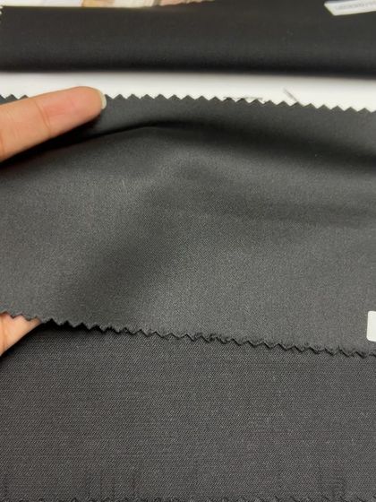 A selection of plain black fabrics, each with a different weight and texture, for classic suits and trousers.