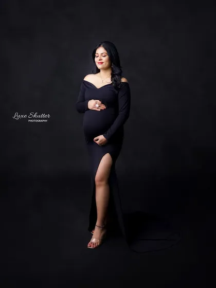 The classic black gown is always a favorite for its timeless elegance. This portrait focuses on the beautiful curves of pregnancy with simple, focused lighting against a dark, dramatic backdrop.