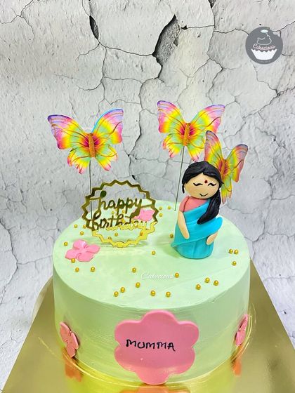 A sweet and simple cake for Mom. The design features a cute caricature of a mother in a saree, surrounded by butterflies.