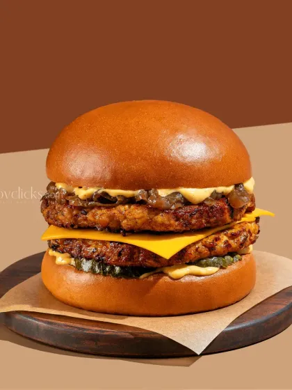 A perfectly stacked double-decker burger with melted cheese and fresh toppings, captured with clean, bright lighting to emphasize its juicy, appetizing details.