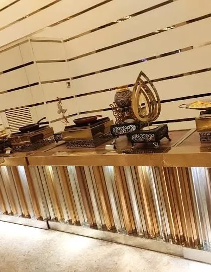 A modern buffet station with a metallic, vertically striped counter and unique, artistic serving dishes. This setup is ideal for contemporary and corporate events.
