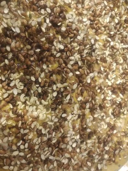 A large tray of Shahi Tukda or a similar bread-based dessert, generously topped with fried nuts and seeds. It's a rich and indulgent sweet.