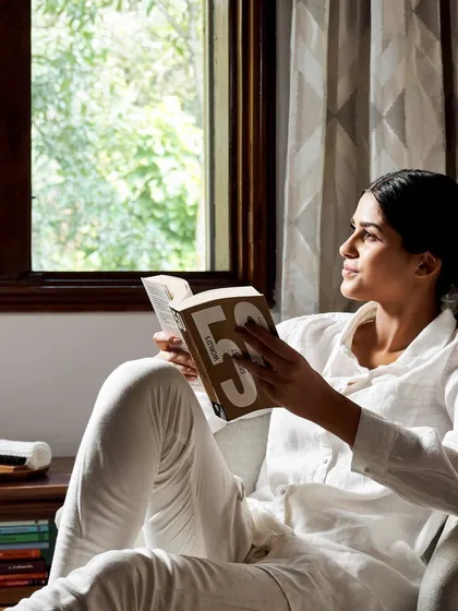 Find a quiet moment to come home to yourself. A guest enjoys a peaceful afternoon reading in the comfort of her heritage cottage, with natural light and the lush greenery of our campus just outside her window. This is the essence of an Ayurvedagram retreat: simple, serene, and deeply restorative.