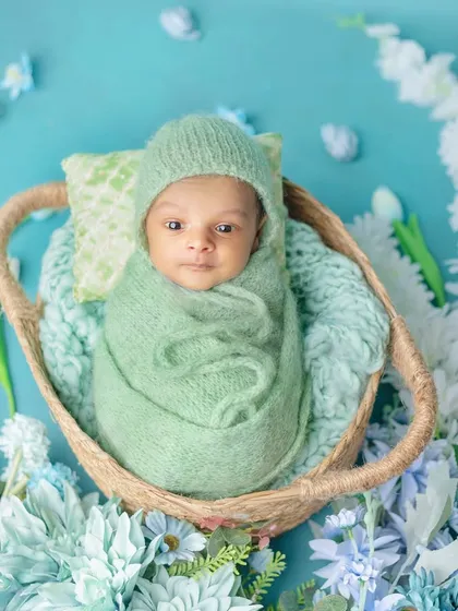 An awake newborn looking curiously at the camera from his cozy basket.