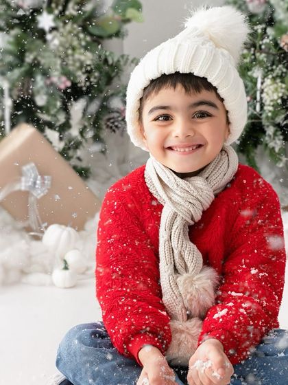 A warm smile to match a cozy red sweater. The falling snow effect adds a touch of magic to this happy Christmas portrait.