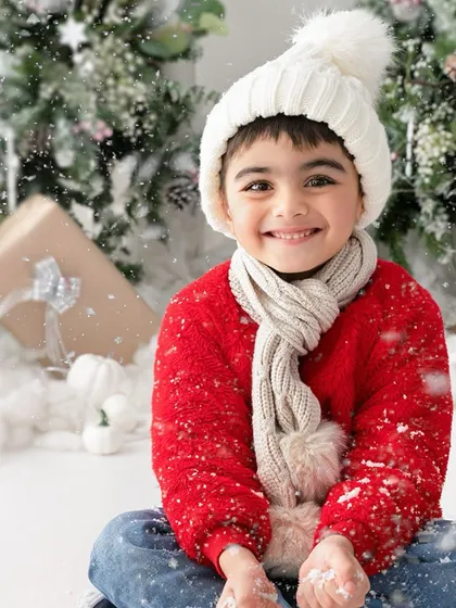 A warm smile to match a cozy red sweater. The falling snow effect adds a touch of magic to this happy Christmas portrait.