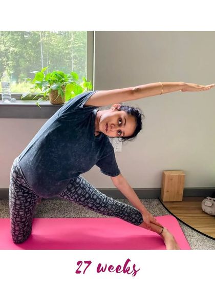 At 27 weeks, this mama is using a chair for support in a standing balancing pose, showing how props can make yoga accessible.