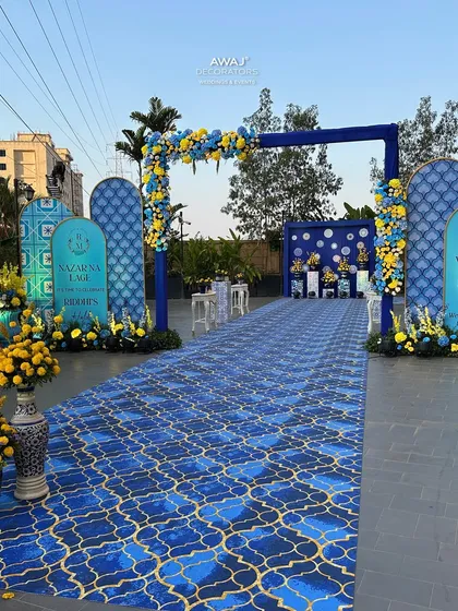 The full view of the blue and yellow themed Haldi entrance, showcasing the custom welcome signs and large floral arrangements in traditional vases.