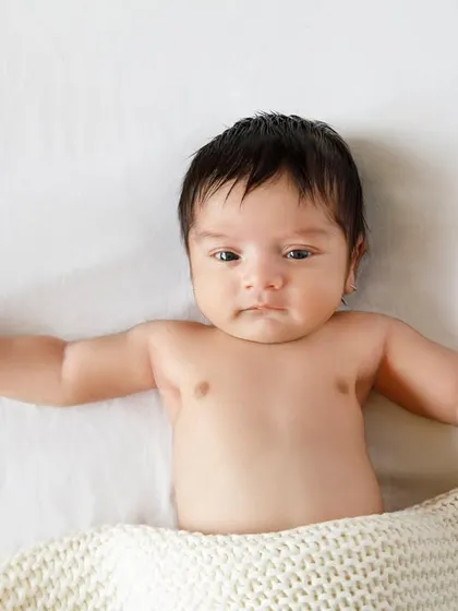 Waking up and stretching. This little one shows off their tiny chest and arms, a simple and beautiful moment from a newborn session.