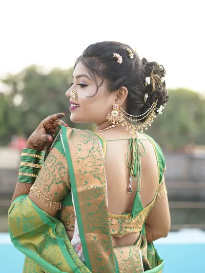 A back view of a bride in a green saree, showcasing her intricate hairstyle with a traditional hair accessory.