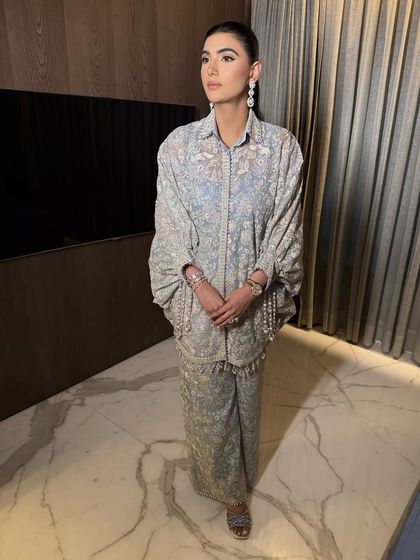 A full-length view of this graceful and elegant look. The minimal makeup complements the soft blue and intricate embroidery of the outfit perfectly.