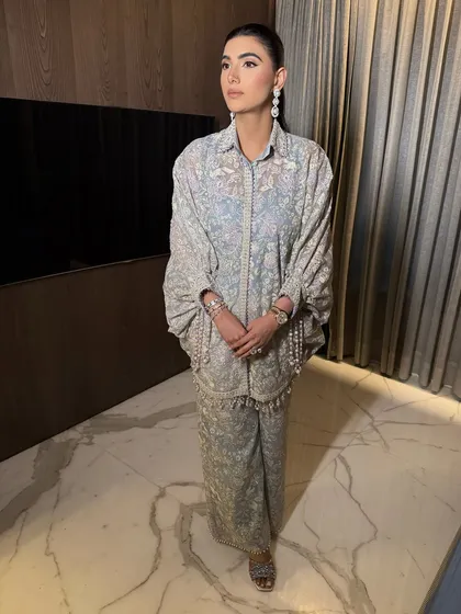 A full-length view of this graceful and elegant look. The minimal makeup complements the soft blue and intricate embroidery of the outfit perfectly.