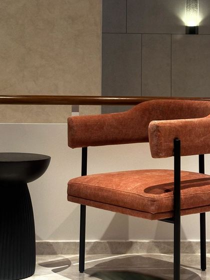 This statement chair, upholstered in a beautiful rustic orange fabric, is styled here for a residential lounge space. Its clean lines and simple black frame allow the color and texture to stand out.