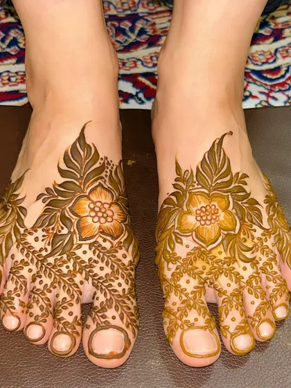 A delicate and pretty foot design with a central flower and a net pattern made of leaves covering the toes.