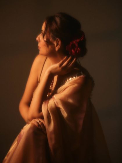 A close-up focusing on the details. The soft focus and the flower in her hair add a touch of romance to this elegant portrait, showcasing the collaborative work with our hairstylist.