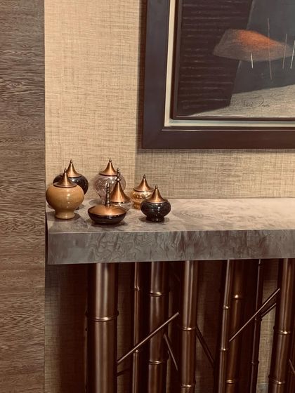 A collection of small, decorative urns on a console with a bamboo-inspired base, showcasing a blend of traditional and modern forms.