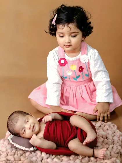 Welcoming a new member to the family is a special milestone. This sibling photoshoot captures the gentle curiosity and love between an older sister and her new baby brother.