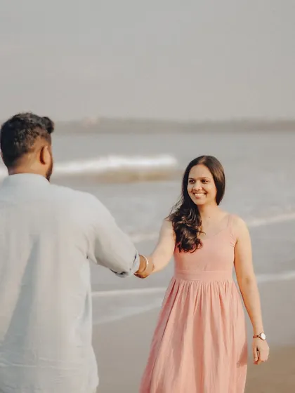 A joyful, candid moment captured as the couple interacts by the water. Her smile towards the camera feels natural and inviting.